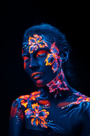 Beautiful flowers in UV light on a young girl face and body